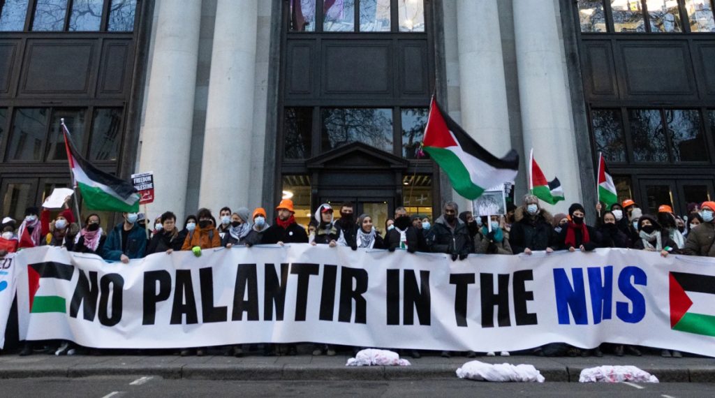 A protest for Palestinian rights with a large banner saying 'No Palantir in the NHS'. Photo by Talia Woodin.